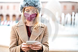 Addicted woman with protective masks using tracking app on mobile smartphone - Young worried millenial sharing content online