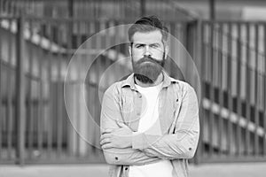 Adding care to his mustache. Serious guy wearing beard and mustache on urban background. Bearded man with stylish