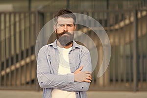 Adding care to his mustache. Serious guy wearing beard and mustache on urban background. Bearded man with stylish