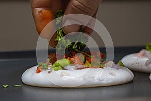 adding coriander leaves on freshly baked utappam on hot non stick tawa