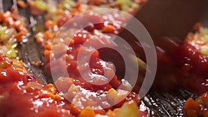 Adding dense tomato sauce to roasting vegetables. Close up video