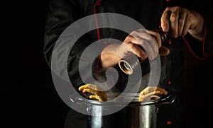 Adding dry pepper with the cook hands to a pan of boiling chicken legs. The concept of preparing a side dish or rich soup in the