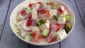 Adding green olives to Greek salad. Traditional Greek dish. Healthy vegetarian food. Fresh vegetables and feta cheese.