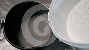 Adding hardener to a bucket of plaster. The white solution is poured into a bucket. photo