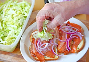 Adding lettuce to smoked salmon sandwich