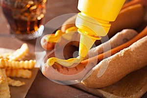 Adding mustard to grilled hot dog