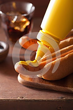 Adding mustard to grilled hot dog