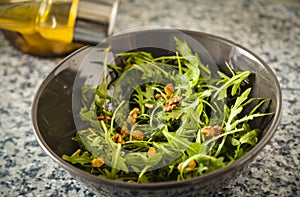 Adding olive oil to an arugula and nuts salad.