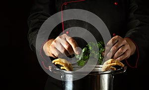 Adding parsley with the chef hands to a pan of boiling chicken legs. The concept of preparing a side dish or rich soup in a