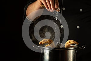 Adding salt with the chef hands to a pot of boiling chicken legs. Concept of preparing a delicious side dish in a restaurant or