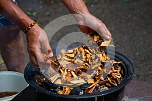 Adding soaked wood chips to the burning charcoal For Smoking Meat On Barbecue.