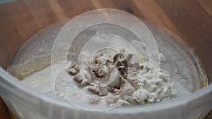 Adding some bread making ingredients (fresh yeast, water, yoghurt, salt, olive oil and sugar) in a large plastic bowl.