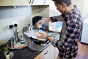 Adding some cheese for extra flavour. a handsome young man cooking in the kitchen at home.