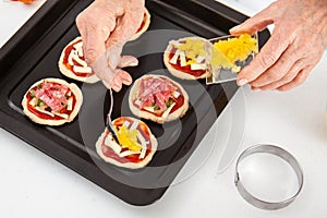 Adding toppings to the mini pizzas. Adding pineapple to the Hawaiian pizza. Delicious homemade mini pizzas preparation