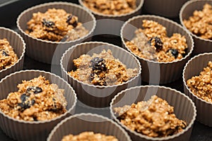 Adding wheat bran muffins mix to the baking cups