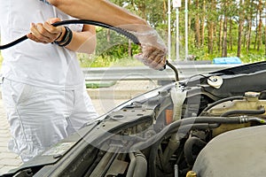 Adding windshield washer fluid at gasolin station by driver. Close-up of adding windshield washer fluid on a car. car