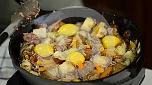 Addition of raw eggs unto a cast-iron frying pan.