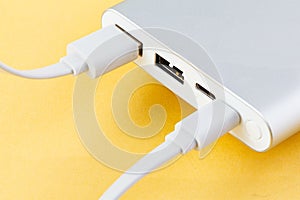 An additional stand-alone power bank for charging mobile devices. External battery on a yellow background. White charger for