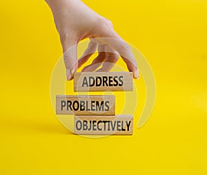 Address Problems Objectively symbol. Wooden blocks with words Address Problems Objectively. Beautiful yellow background.