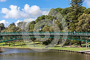 The Adelaide University Footbridge over river Torrens Karrawirra Parri. People at the park walking, fishing, riding a bike.