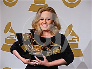 Adele holding trophys at the Grammy Awards
