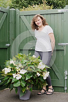 Adele standing beside a white container grown begonia.