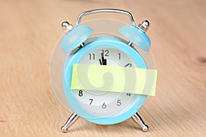 Adhesive note on a blue alarm clock