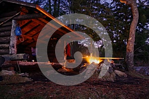 Adirondack Lean to Bushcraft camp shelter with fire at night in the mountains.