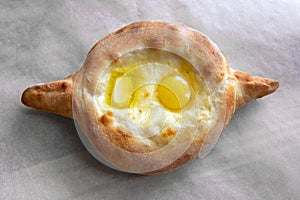 Adjara khachapuri - cheese pie with egg yolk and butter on paper