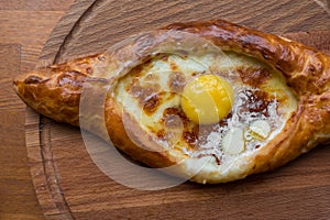 Adjara khachapuri on a wooden plate top view close up