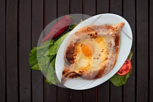 Adjarian khachapuri with eggs on wooden table