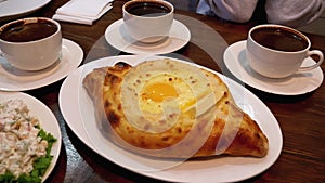 Adjarian Khachapuri on a Table in a Georgian Restaurant next to Salad, Omelette and Coffee