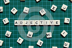 Adjective word made of square letter word on green square mat background. photo