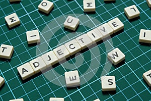 Adjective word made of square letter word on green square mat background.