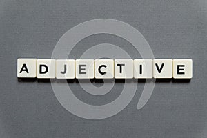 Adjective word made of square letter word on grey background.