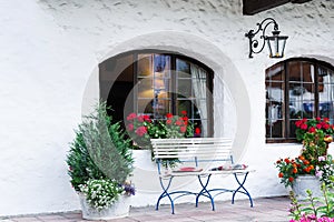 The adjoining territory is decorated with a white bench, flowers and a forged lantern