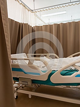 The adjustable hospital bed with a patient lying in the white blanket