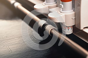 adjustable knife of plotting machine cuts high detail tiger striped lettering from black adhesive foil photo