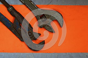 Adjustable and pipe wrenches against the background of an orange