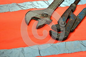 Adjustable and pipe wrenches against the background of an orange signal worker shirt. Still life associated with repair, railway