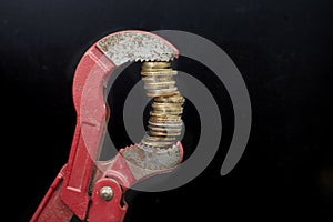 adjustable plumber's wrench holding a high stack of coins.