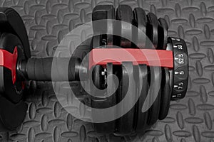Adjustable weight dumbbell in plastic polymer material on black rubber floor.