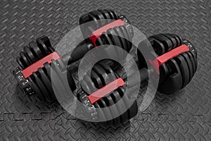 Adjustable weight dumbbell in plastic polymer material on black rubber floor.