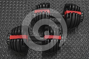 Adjustable weight dumbbell in plastic polymer material on black rubber floor.