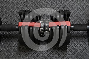 Adjustable weight dumbbell in plastic polymer material on black rubber floor