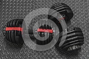 Adjustable weight dumbbell in plastic polymer material on black rubber floor