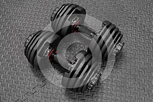 Adjustable weight dumbbell in plastic polymer material on black rubber floor