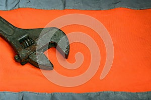 Adjustable wrench against the background of an orange signal worker shirt