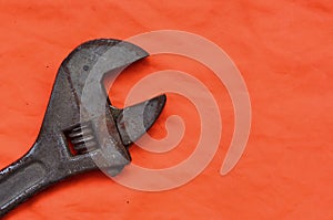 Adjustable wrench against the background of an orange signal worker shirt