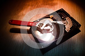 Adjustable wrench turn off a hard disk. On a dark background. Computer repair concept